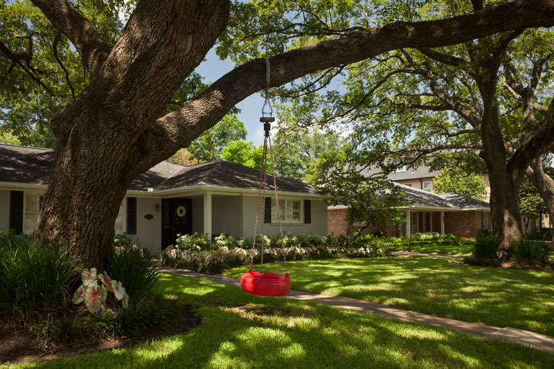 House with a tree in front and a swing made from tire