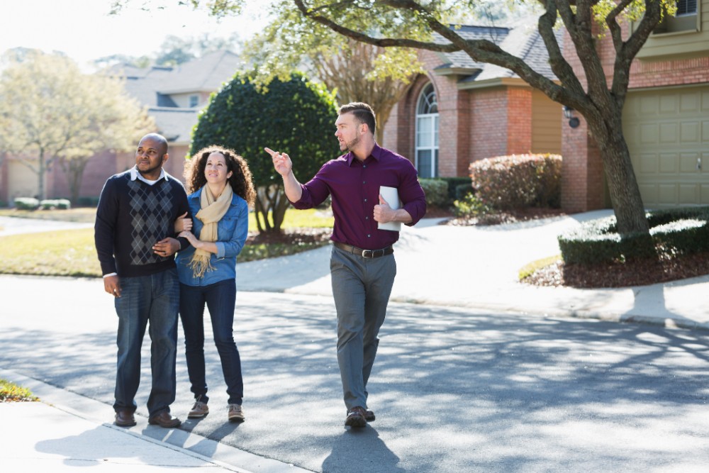 Black Couple Walking On Residential Street With Agent