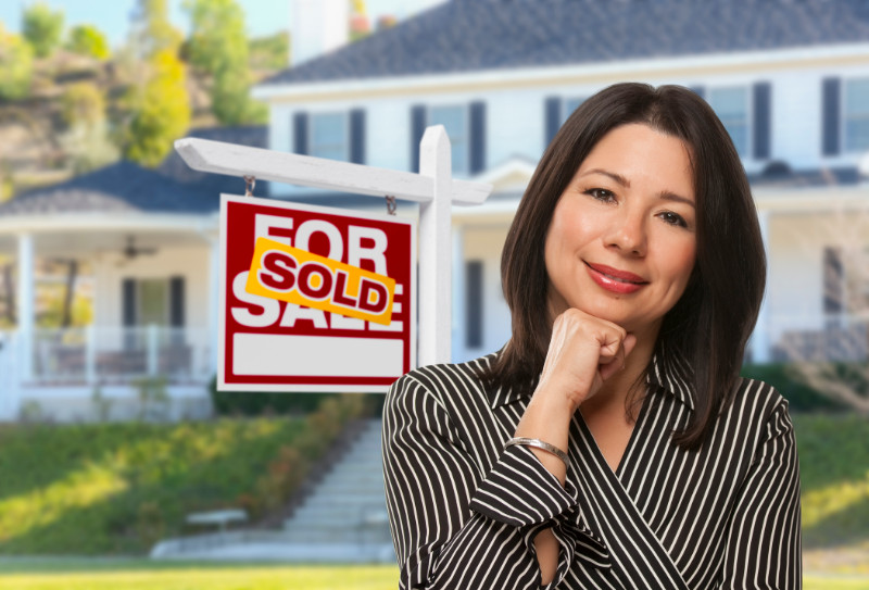 A woman in front of a sold house